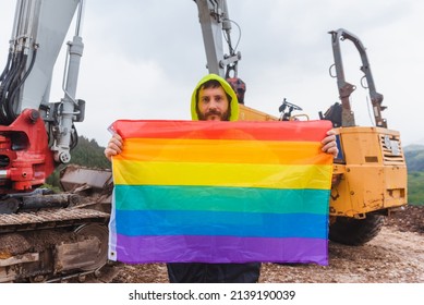 Working Man On A Construction Site Holding A Rainbow Lgbt Pride Flag Demanding Equal Treatment At His Job. Concept Of Sexual Discrimination In Employment.