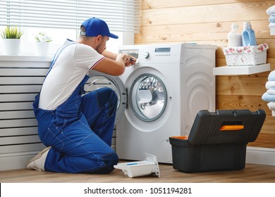 working man plumber repairs a washing machine in   laundry