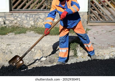 A Working Man In Uniform Holding A Shovel In His Hands At A Highway Construction Site