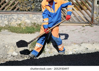 A Working Man In Uniform Holding A Shovel In His Hands At A Highway Construction Site