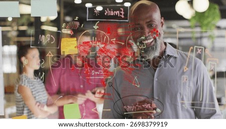 Working mature black man annotating diagrams on glass board in office, with red world map. Collaboration, teamwork, innovation, brainstorming, modernoffice, businessstrategy, creativity