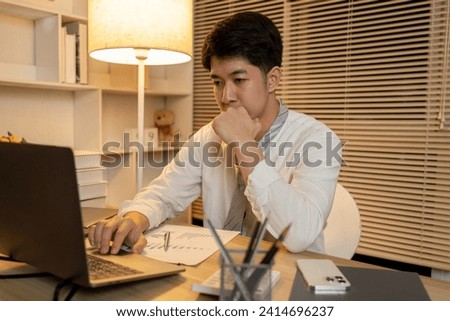 Working in the middle of the night, Man sat typing away on a laptop in his office with a determined look on his face, Male hand pressing on laptop keyboard.
