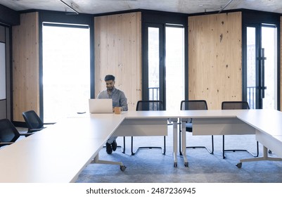 Working in modern office, man using laptop and drinking coffee at desk, copy space. Business, workspace, productivity, professional, entrepreneur, technology