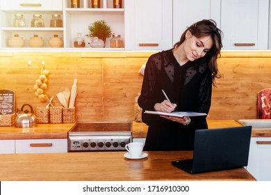 Working Mom With Makeshift Office Set Up In The Kitchen Wearing Black Dress