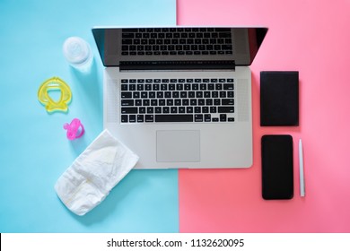 Working mom top view flatlay of workplace baby items and laptop with phone