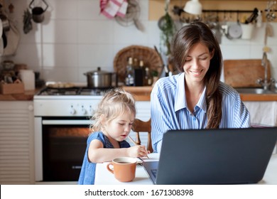 Working mom works from home office with kid. Happy mother and daughter. Woman and cute child using laptop. Freelancer workplace in cozy kitchen. Female business, career. Lifestyle family moment.
