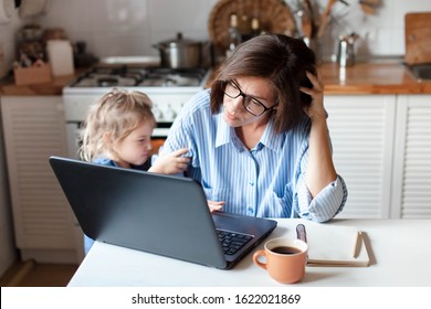 Working Mother In Home Office. Unhappy Woman And Child Using Laptop. Sad And Angry Daughter Needs Attention From Busy Exhausted Mom. Freelancer Workplace In Kitchen. Female Business. Lifestyle Moment.