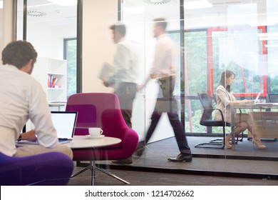 A Working Office With People Walking Out Of Focus, Concept Of A Real Life Busy Office Environment