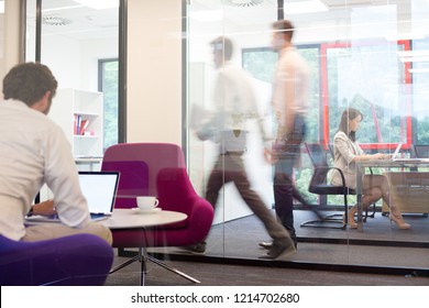 A working office with people walking out of focus, concept of a real life busy office environment