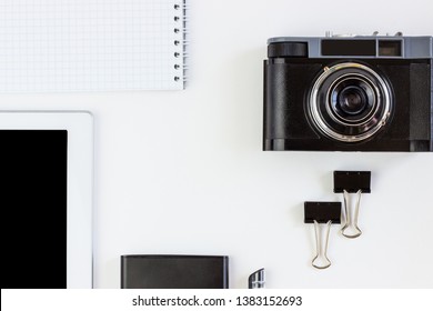 Working office space with a tablet, notepad, camera, external hard disk located on a white table, top view, flat lay, copy space.