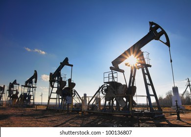 working oil pumps silhouette against sun - Shutterstock ID 100136807