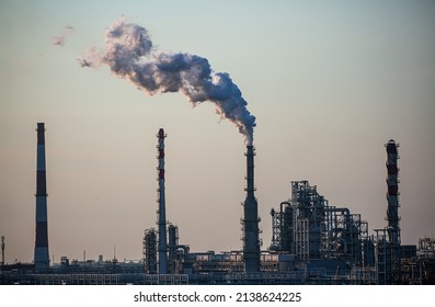 Working oil refinery. Smoke from the factory chimney. Ecological pollution. Air emissions polluting the city. Industrial waste is hazardous to health. Large factory in smog, Production in operation. - Powered by Shutterstock