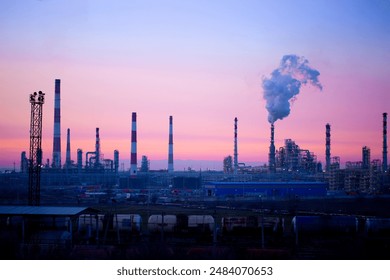 Working oil refinery. Smoke from the factory chimney. Ecological pollution. Air emissions polluting the city. Industrial waste is hazardous to health. A large working factory in the smog at sunset. - Powered by Shutterstock