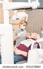 Working On Beautiful Smile. Handsome Senior Healthy Man Sitting In Dentist Chair While His Dentist Is Using Some Tools For Treating His Teeth. Stomatology Concept. Stock Photo