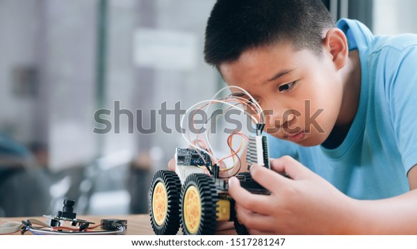 Working on Handmade car model,\
construction on electronic. Concentrated boy creating robot at lab.\
Early development, diy, innovation, modern technology\
concept.