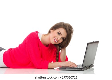 Working On A Laptop. Young Woman Is Laying Down On A Floor And Using Laptop. Waist Up Studio Shot Isolated On White.