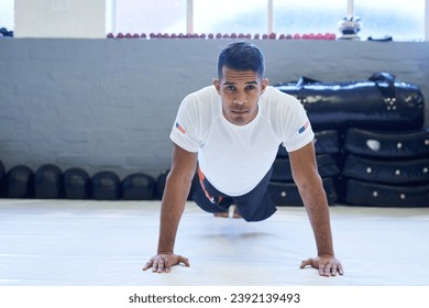 Working on my upper body strength. Portrait of a young man doing pushups in the gym. - Powered by Shutterstock