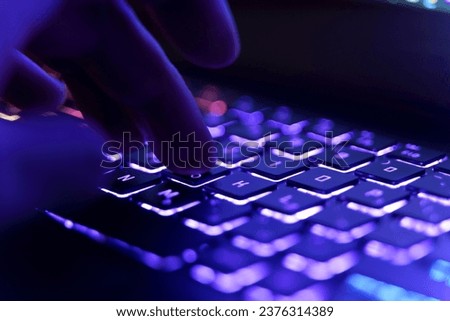 Working on a neon computer keyboard with colored backlighting. Selected focus. Computer video games, hacking, technology, internet concept. Selected focus.