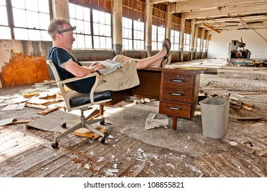 Working On An Old Computer At A Desk Inside An Abandoned Factory.