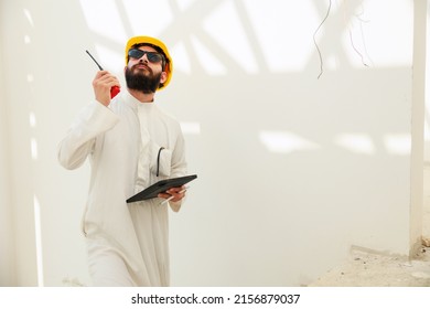 working on tablet and walkie talkie. Arab man Construction civil engineer use digital tablet computer and wearing in safety hard hat helmet working on Building Site. talki, walki - Powered by Shutterstock