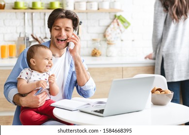 Working On Weekends. Cheerful Dad Consulting Clients By Phone, Working With Cute Baby Son At Home Kitchen, Free Space