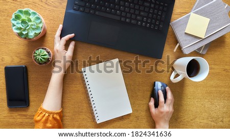 working on a wooden desk with a laptop computer, notebooks, coffee, smartphone seen from above