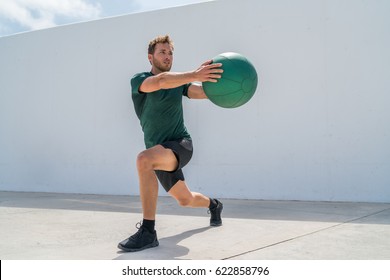 Working out man training legs and core ab workout doing lunge twist exercise with medicine ball weight. Gym athlete doing lunges and torso rotations for abs training.