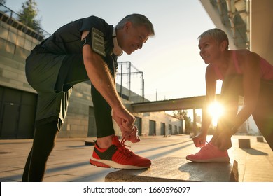 Working out together. Fit and healthy senior couple in sports clothing tying shoelaces before jogging outdoors. Fit, fitness, exercise. Healthy lifestyle concept. Exercising together