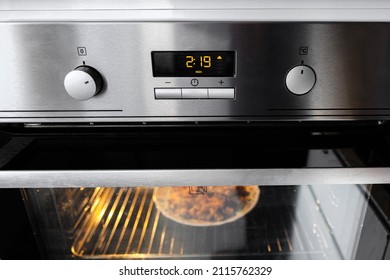 A working oven with a timer heats food. Inox oven. Chrome oven.