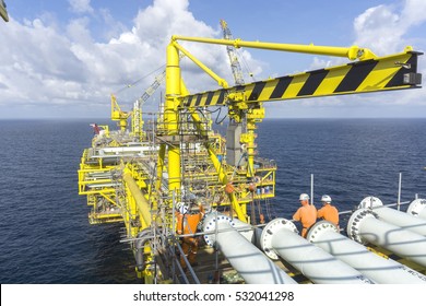 Working Overboard. Working At Height. Offshore Workers Perform Lifting Activities Using Overhead Crane On Top Of Oil And Gas Rig Platform In The Middle Of South China Sea.