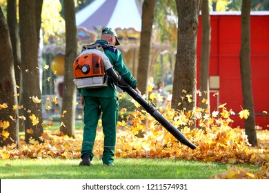 Working in the Park removes autumn leaves with a blower
