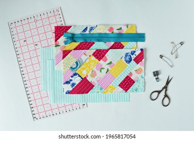 Working Process: Colorful Quilt, Fabric, Zipper, Embroidery Scissors , Quilting Pins, Sewing Foot And Acrylic Ruler On White Background