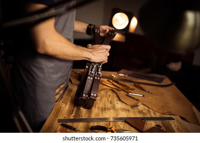 Working process of the leather belt in the leather workshop. Man holding photographer's belt for camera. Tool on wooden background. Tanner in old tannery. Close up master's arm. - Powered by Shutterstock