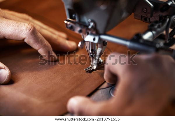 Working process of leather craftsman. Tanner or\
skinner sews leather on a special sewing machine, close up.worker\
sewing on the sewing\
machine