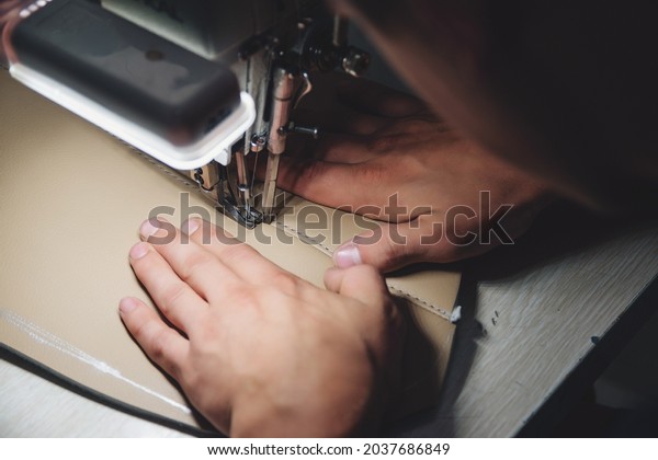 Working process\
of leather craftsman. Tanner sews leather on a special sewing\
machine, close up. Worker sewing leather product on the sewing\
machine. Leather worker\
workshop.