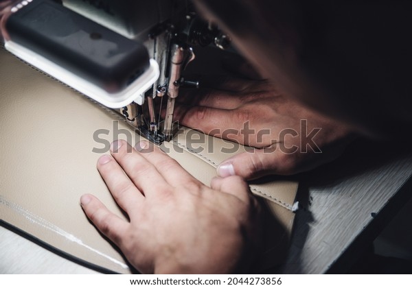 Working process\
of leather craftsman. Tanner sews leather on a special sewing\
machine, close up. Worker sewing leather product on the sewing\
machine. Leather worker\
workshop.