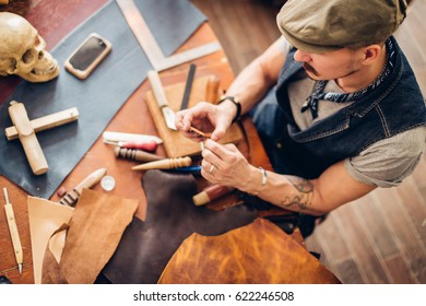 Working process of the leather wallet in the leather workshop. man holding crafting tool and iron ruler