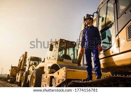 Working process on the construction site. A contractor builder is sitting near excavator. Construction machinery concept