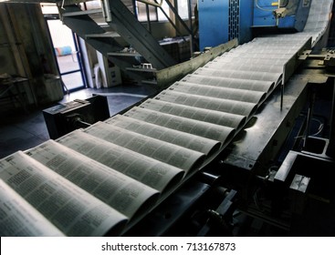 Working process of printing circulation of news newspaper. Tape of conveyor with newspaper running in process. Work of modern printing equipment when printing printed products