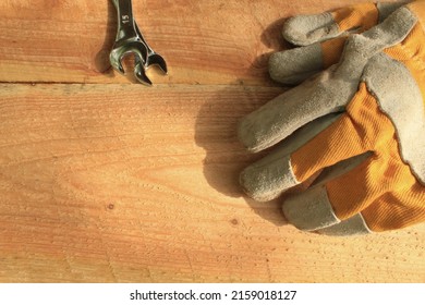 Working Process. Wrench And Heavy Duty Gloves. Wooden Surface.