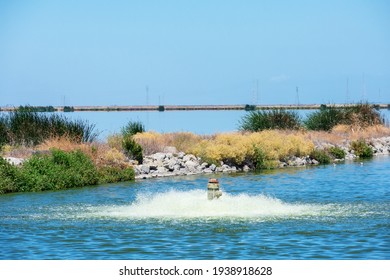 Working Pump Aerating And Filtering Contaminated Water In Wastewater Treatment Facility Pond To Remove Pollutants And Dissolved Gases. Dam Separates Oxidation Ponds.