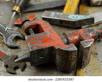 Working and rusty instruments open end wrench, pliers, rasp, bench vice, hammer, awl  lie on the rusty sheets metal  in the workshop
