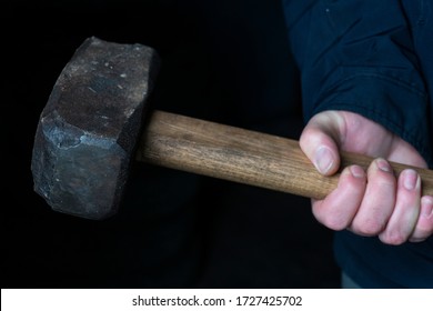 Working Sledgehammer In Hands With Notches For Breaking Walls On A Dark Background