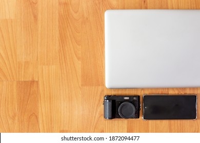 Working table with computer laptop, smartphone, digital camera and copy space on wood desk background, Top view style, Minimal workspace, business Concept - Powered by Shutterstock