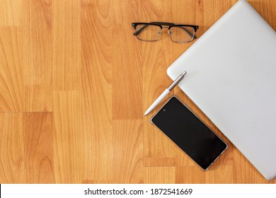 Working table with computer laptop, smartphone, pen, glasses and copy space on wood desk background, Top view style, Minimal workspace, business Concept - Powered by Shutterstock