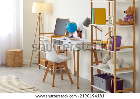 Working table in kid's room. Interior and design of modern bright and spacious children's room for preteen child. Child space with table, shelf, books and toys indoors at home in apartment