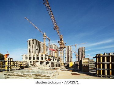 Working tall cranes inside place for with tall buildings under construction under a blue sky - Powered by Shutterstock