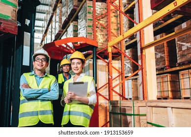 Working Team At Warehouse. Manager Man And Asian Woman Warehouse Worker Standing With Crossed Arms To Look At The Camera.background Driver At Warehouse Forklift Loader Works With Goods