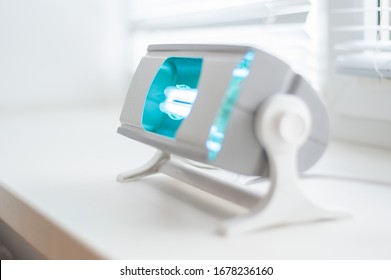 A Working Ultraviolet Lamp On A White Background. The Concept Of Protecting And Cleaning Rooms And Objects From Bacteria And Viruses. Medicine And Healthcare.