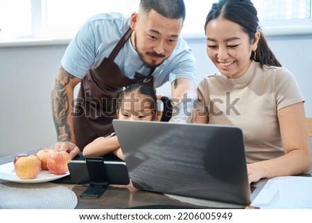 Working woman behind laptop, next her husband and little daughter